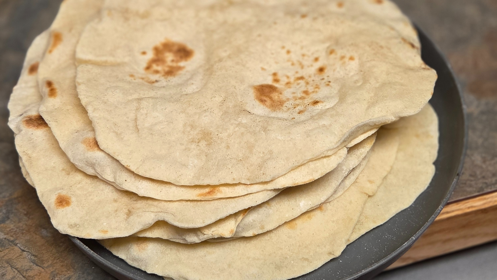 Homemade sourdough tortillas piled on a plate