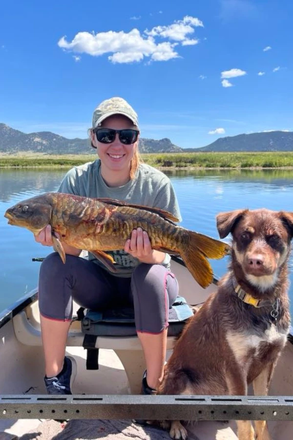 Bowfishing for beginners. woman with carp shot with a bow and her dog along side her