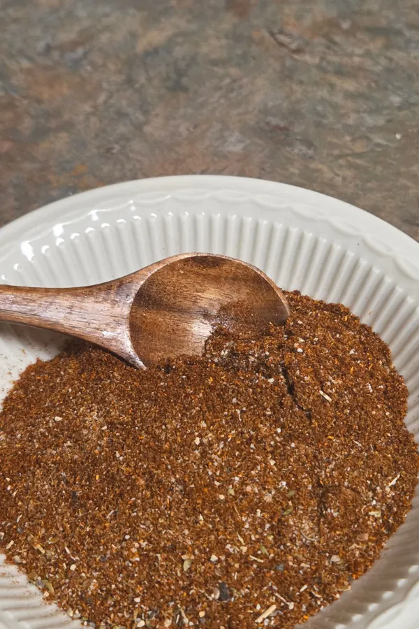 homemade fajita seasoning blend on a white plate with a wooden spoon